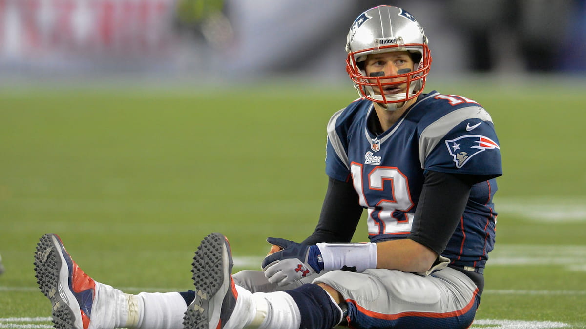 Tom Brady of the Patriots sitting in the center of the field.