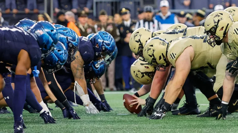 Army and Navy football teams line up against each other at line of scrimmage.
