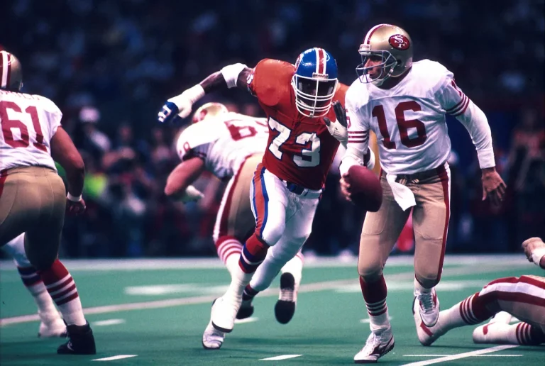 49ers quarterback Joe Montana scrambles with the ball away from a Denver Broncos defender in the Super Bowl.